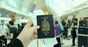 An air traveller holds a Canadian passport in their hand.