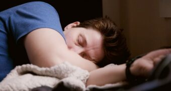 A photo of a person sleeping with their arm covering their mouth. (Photo: theyshane / Unsplash)