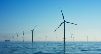 A dozen wind turbines rise out of the water, generating renewable energy.