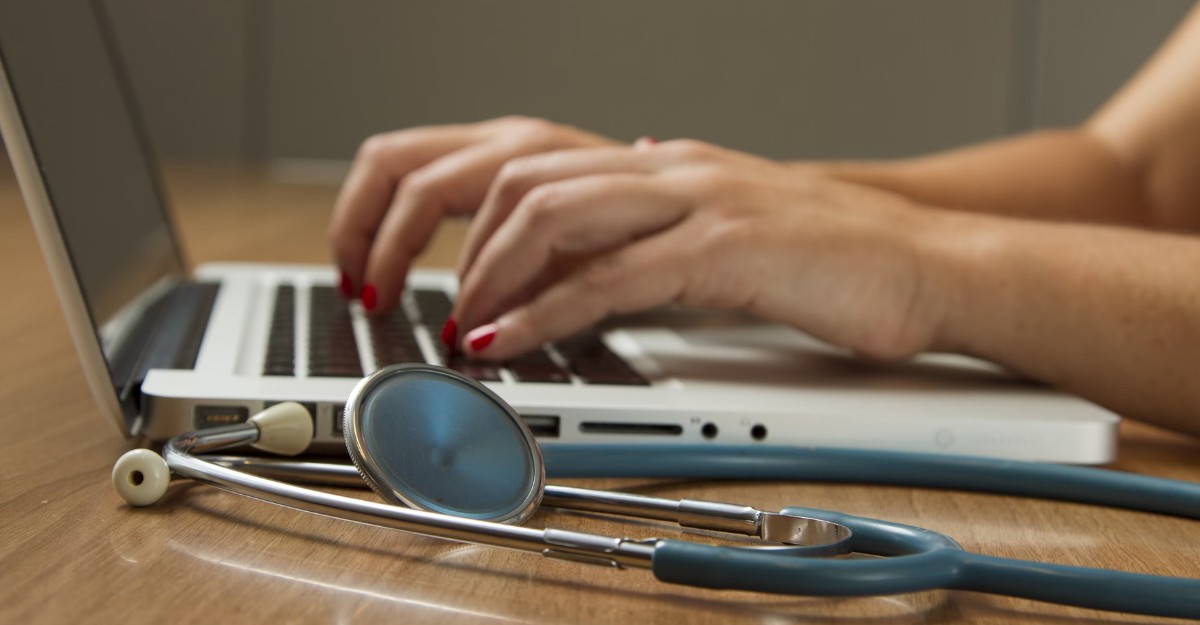 telus-health-acquires-workplace-options-rights A photo of a person using a laptop with a stethoscope beside them. (Photo: National Cancer Institute / Unsplash)