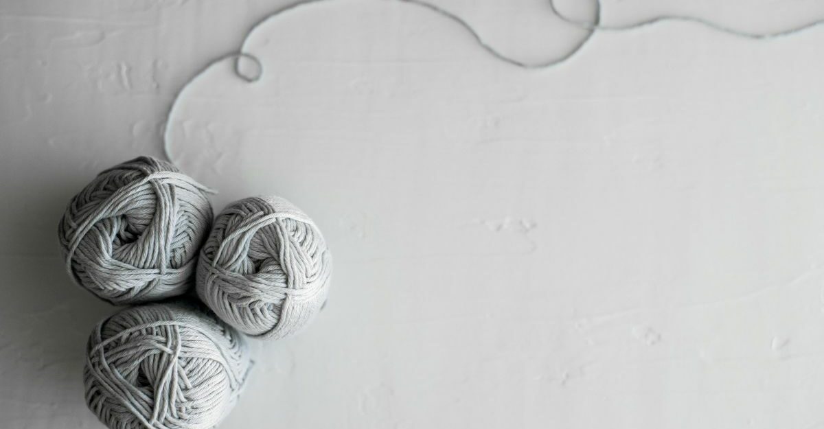 balls-of-yarn Three balls of yarn are clumped together, with a a light grey thread extending from one.