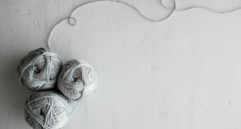Three balls of yarn are clumped together, with a a light grey thread extending from one.