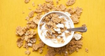 A photo of a bowl of cereal covered in milk on a yellow table. (Photo: Nyanastoica / Unsplash)