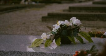 Flowers are seen on top of a tombstone at a local cemetry. (Unsplash)
