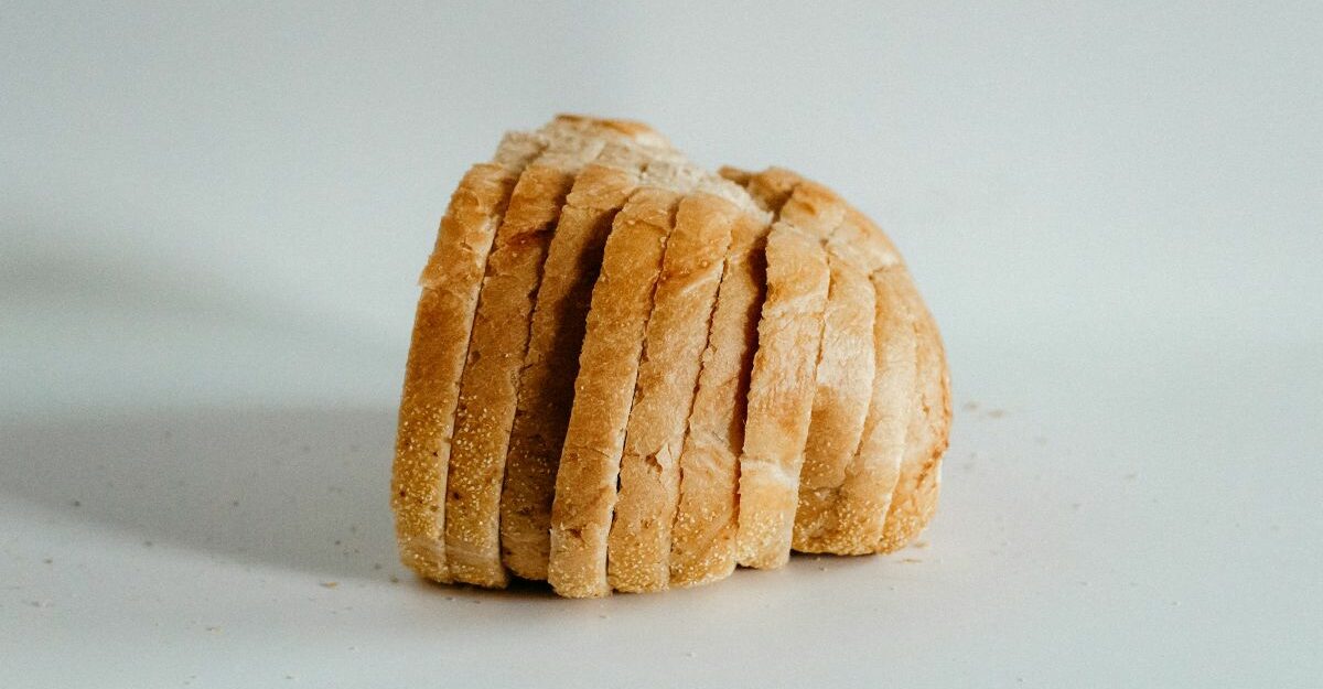 A loaf of bread, cut into slices, sits on a surface.