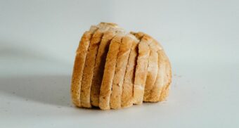 A loaf of bread, cut into slices, sits on a surface.