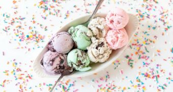 A bowl of ice cream surrounded by sprinkles on a white table. (Photo: Courtney Cook / Unsplash)