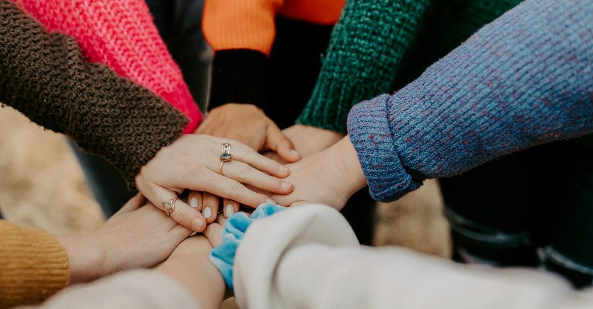 A group of people standing in a circle with their hands stacked in the middle.