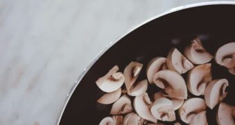 Raw mushrooms sit in a frying pan, ready to be cooked.