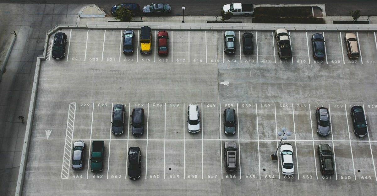 A bird's-eye view of a parking lot featuring dozens of vehicles.
