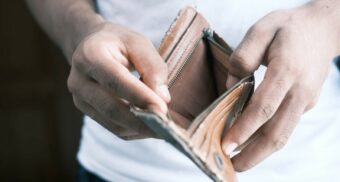 A man opens a brown leather wallet to reveal that it's empty. (Photo: Towfiqu Barbhuiya / Unsplash)