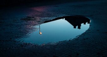 A puddle on a road at sunset. (Photo: alicetricky / Unsplash)