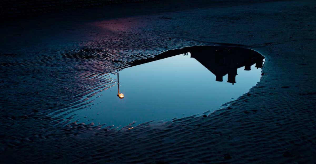 A puddle on a road at sunset. (Photo: alicetricky / Unsplash)