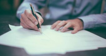 A person reviewing and signing documents at a desk, illustrating how gainful employment decisions and disability claim forms are assessed.