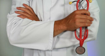 A doctor holding a red stethoscope. (Photo: impulsq / Unsplash)