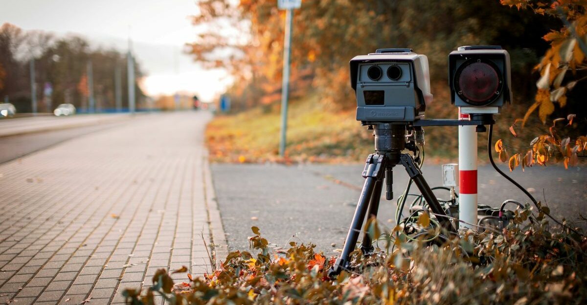 Mobile speed camera set up on a roadside in autumn, used for traffic enforcement.