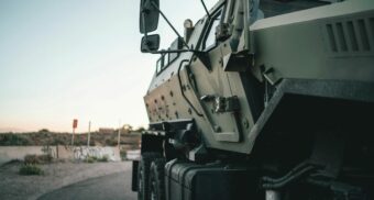 A view of the right side of a new armoured vehicle as it motors down a road.