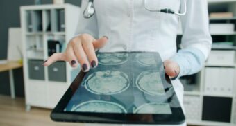 A doctor reviews brain scans on a digital tablet. (Photo: Vitaly Gariev / Unsplash)
