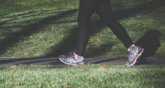 A woman with running shoes on walks through a public park. (Photo: Areksan / Unsplash)