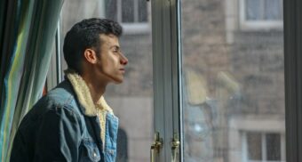 A person looks out a window. (Photo: Abdullah Ali / Unsplash)