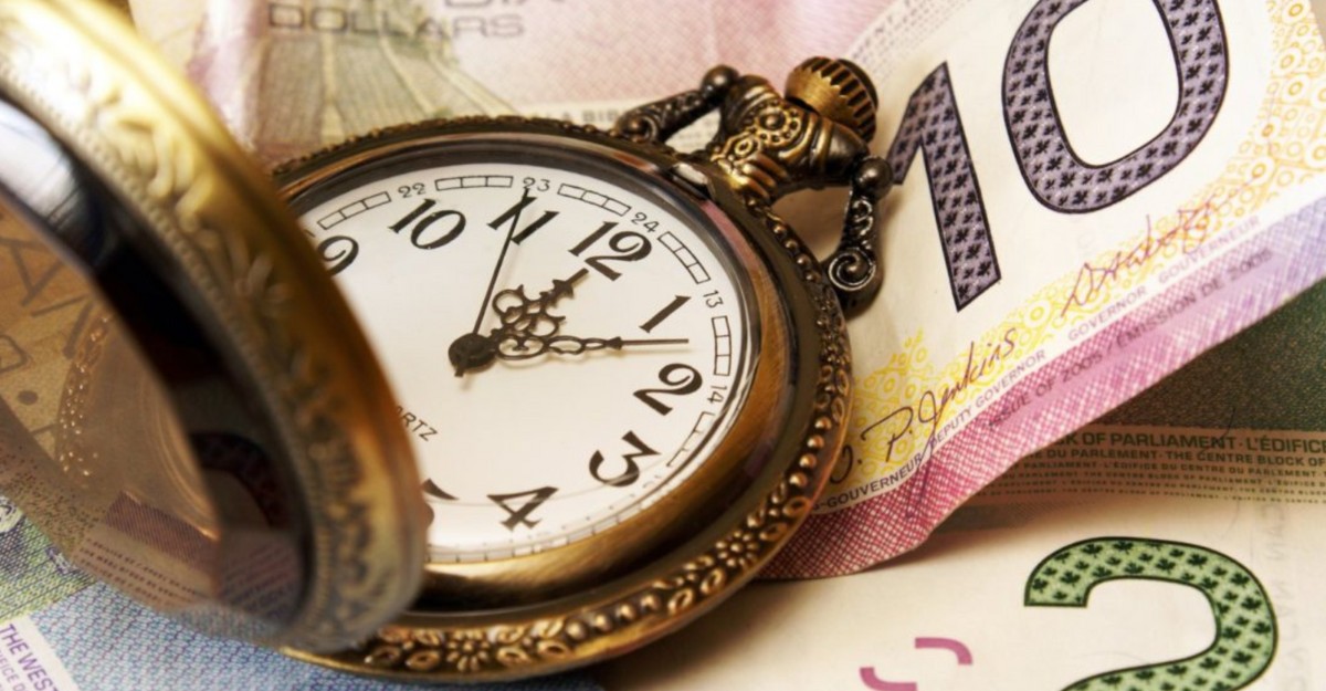 A clock resting on Canadian currency. (Photo: Google Images)