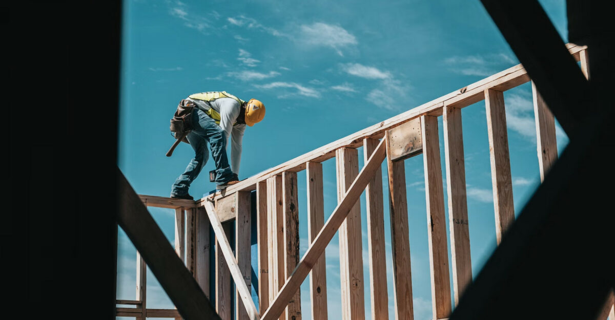 A construction worker securing wooden beams. (Photo: Josh Olalde / Unsplash)