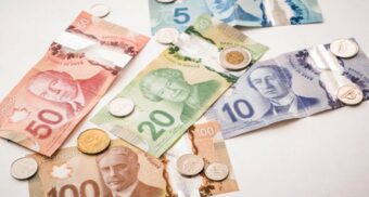 Canadian currency on a table. (Photo: PiggyBank / Unsplash)