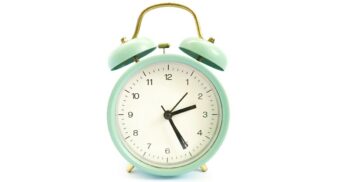 A green clock in front of a white background. (Photo: Abdul A / Unsplash)