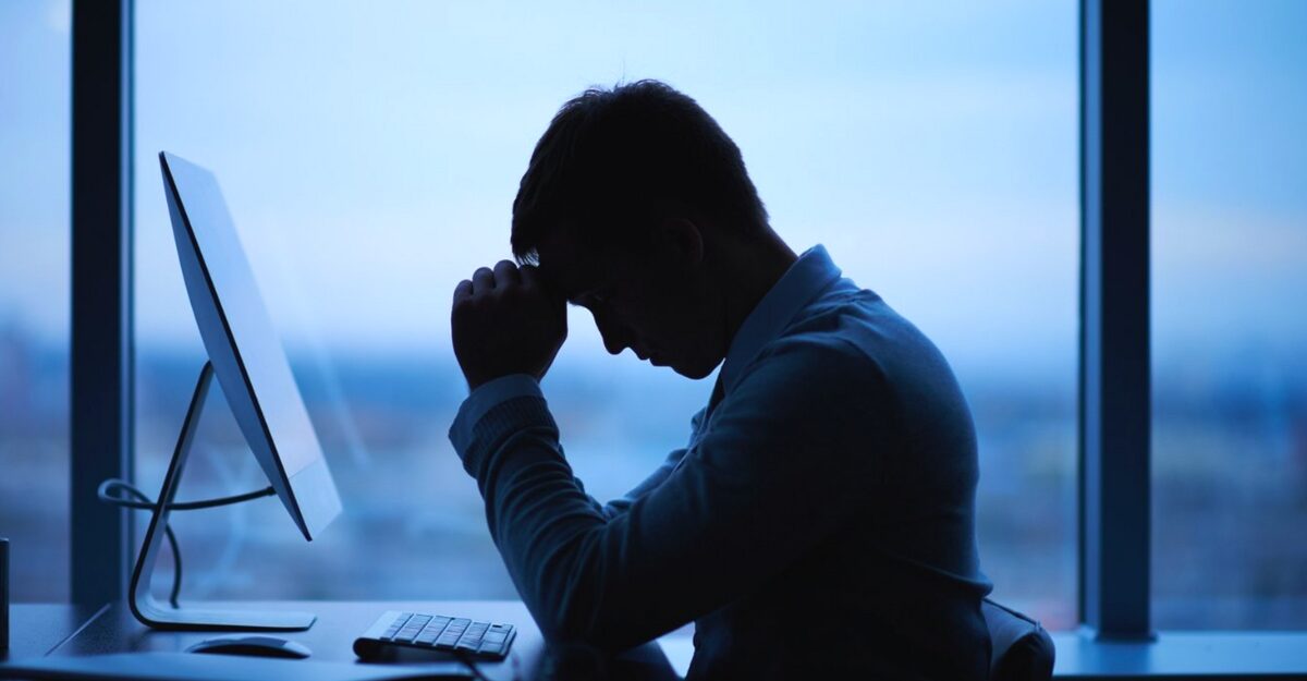A worker with their hands over their face at their desk. (Photo: shironosov / iStock)