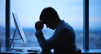 A worker with their hands over their face at their desk. (Photo: shironosov / iStock)