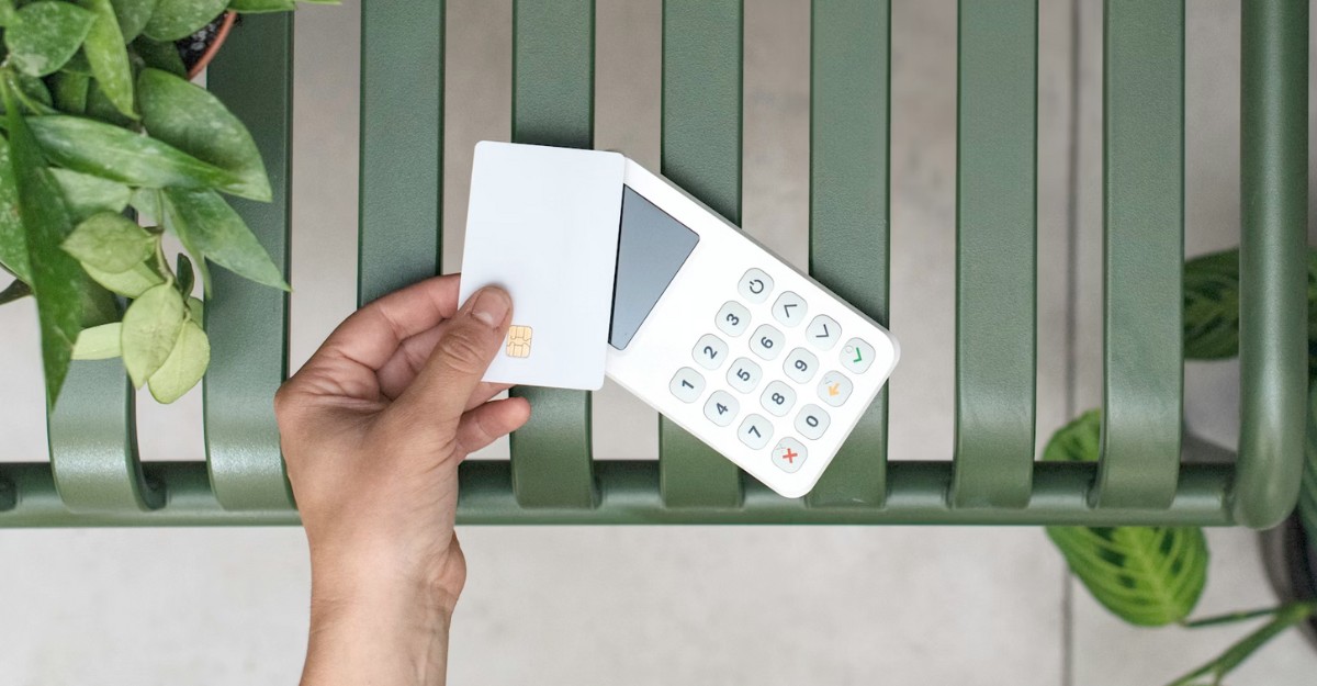 A person taps a credit card on a digital reader. (Photo: Mockuuups / Unsplash)