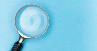 A magnifying glass on a blue background. (Photo: Markus Winkler / Unsplash)