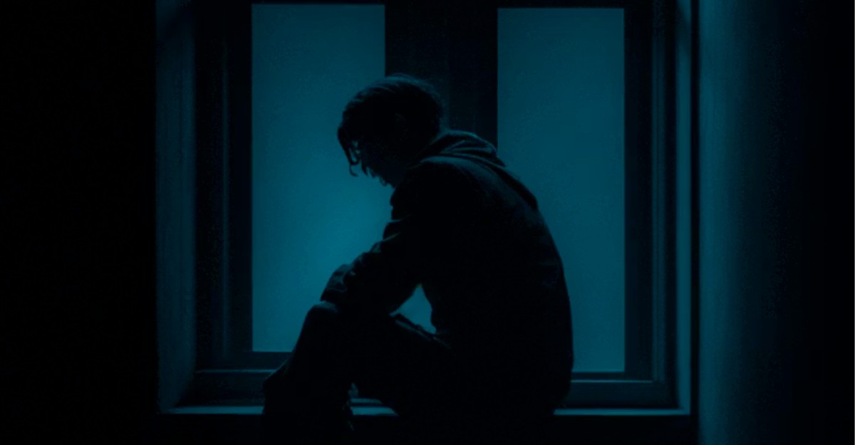 An individual sits near a window in a dark room. (Photo: Satyam Pathak / Unsplash)