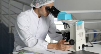 A scientist studies a slide under a microscope. (Photo: Lucas Vasques / Unsplash)