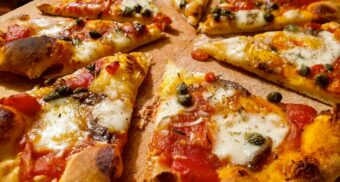 A loaded pizza sitting on a wooden pizza board. (Photo: Henry Perks / Unsplash)