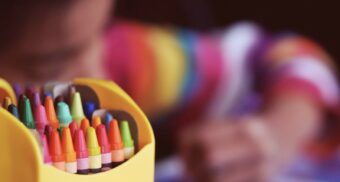 A child uses crayons to create artwork. (Photo: Aaron Burden / Unsplash)