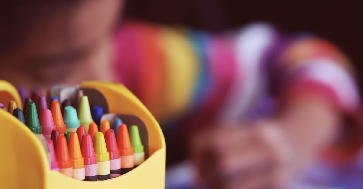 A child uses crayons to create artwork. (Photo: Aaron Burden / Unsplash)