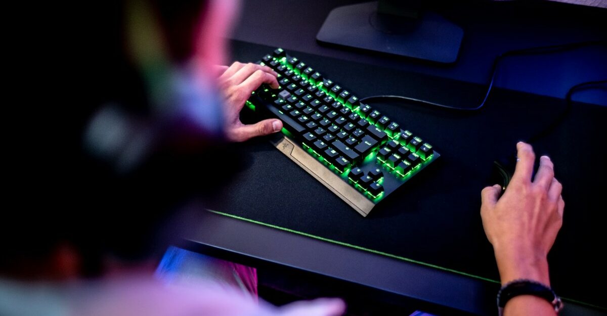 A person with headphones on using a mouse and keyboard. (Photo: ELLA DON / Unsplash)