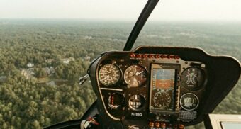A helicopter pilot flying above a forest. (Photo: Isaac Macdonald / Unsplash)