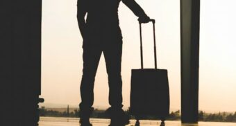 A man standing with his luggage at an airport. (Photo: Yousef Alfuhigi / Unsplash)