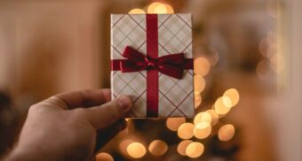 A person holds up a wrapped gift card. (Photo: Rob Laughter / Unsplash)