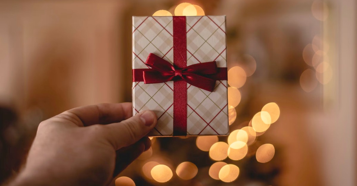 A person holds up a wrapped gift card. (Photo: Rob Laughter / Unsplash)
