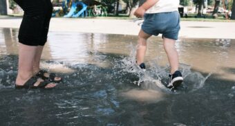 A parent and their child play in a splash pad. (Photo: Logan Cameron / Unsplash)