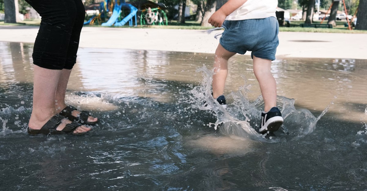 A parent and their child play in a splash pad. (Photo: Logan Cameron / Unsplash)