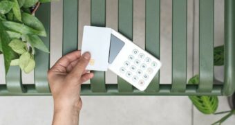 A person taps a credit card on a digital reader. (Photo: Mockuuups / Unsplash)
