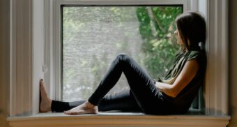 A depressed woman looks out a window. (Photo: Kelly Sikkema / Unsplash)